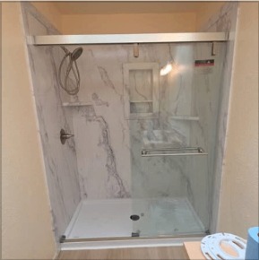 Finished walk-in shower with marble surround and glass door